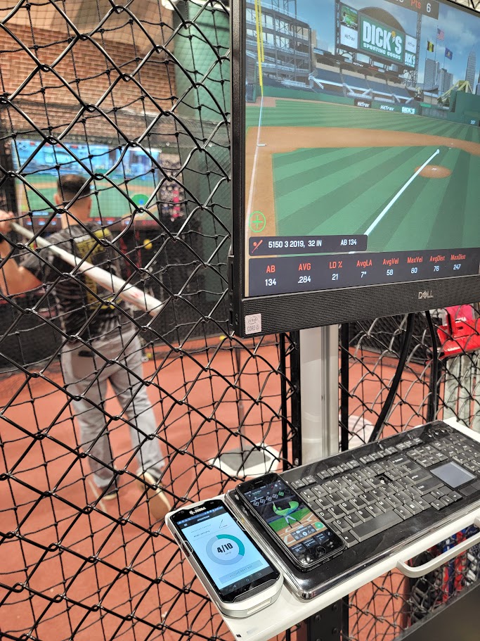 Batting cage kiosk showing swing tracking alongside the bat-fitting handheld